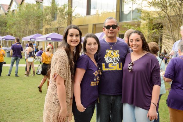 A group of people in LSU gear smile in the BEC courtyard. 