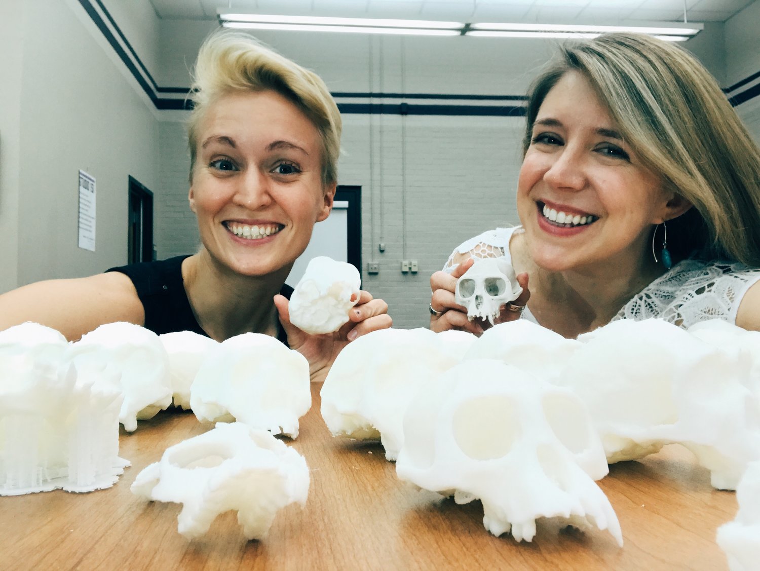 two female scientists posing with 3D-printed skull models 