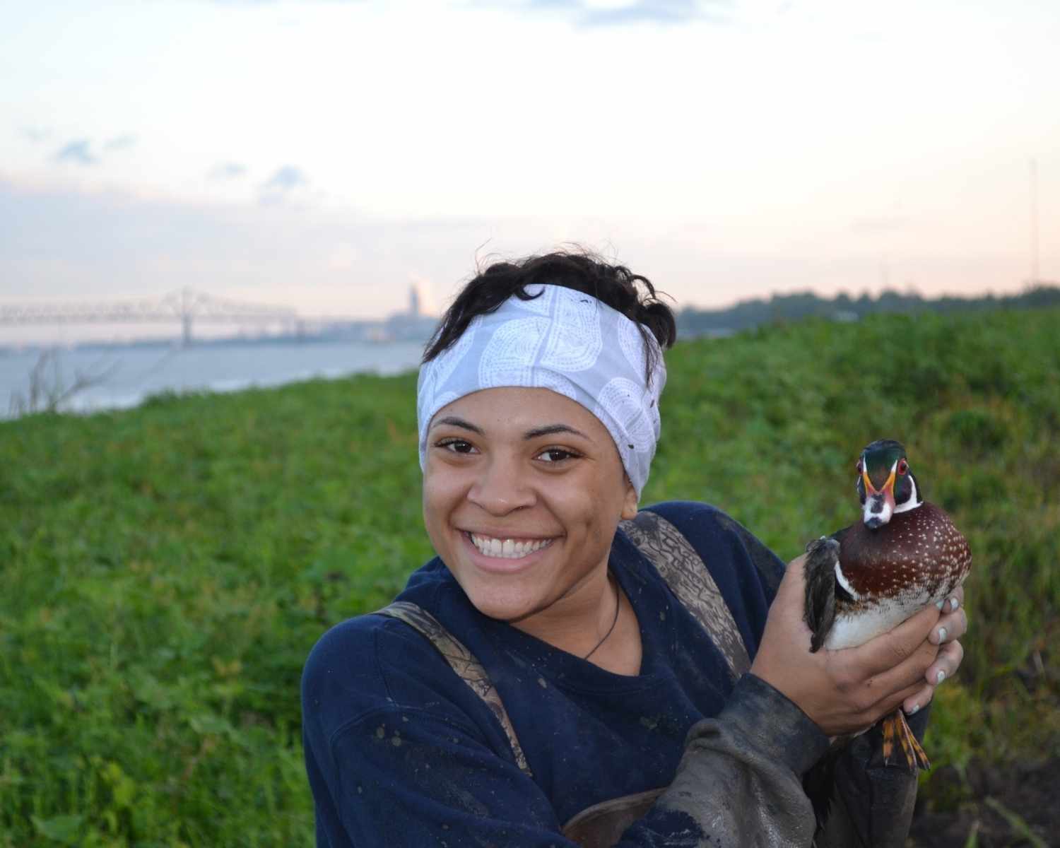 Student holds duck with Baton Rouge bridge in background