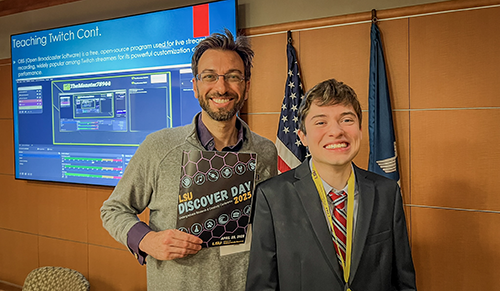 Luke Gilmore and Aaron Gleiberman stand in front of a TV screen at LSU Discovery Day 2025