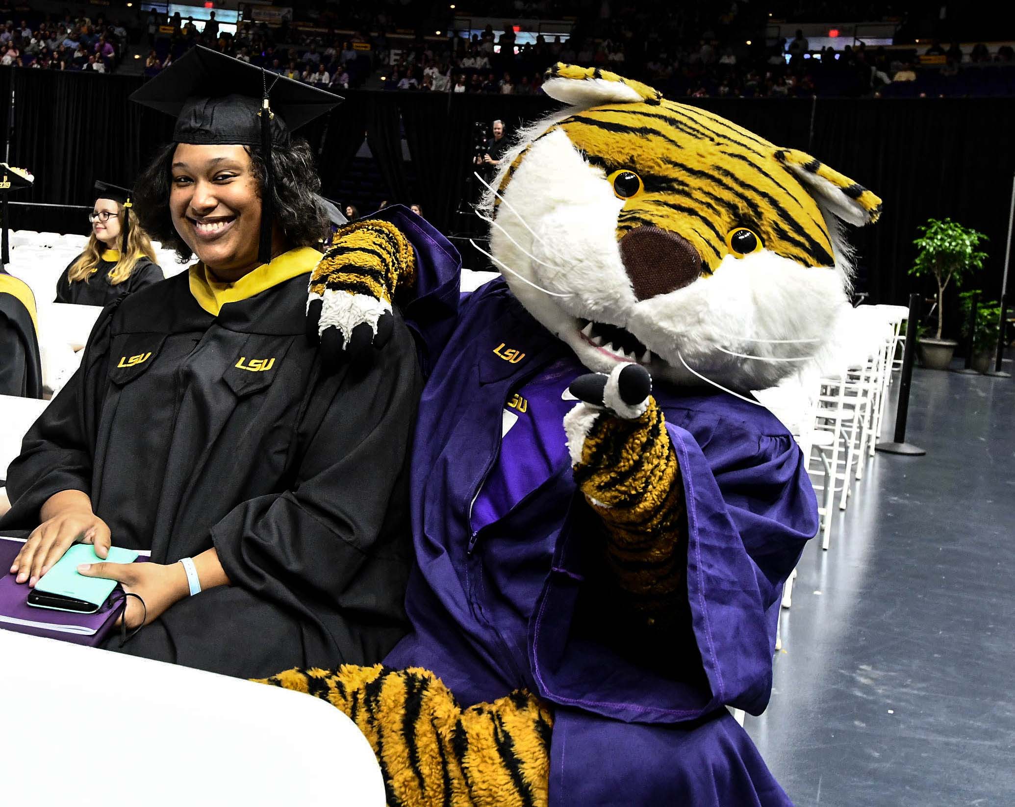 Black female and Mike the Tiger in graduation gowns and caps