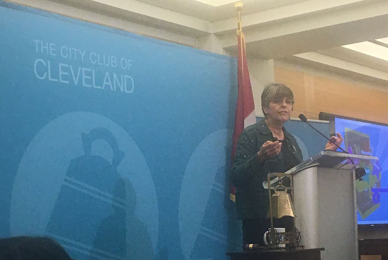 Mary Beth Tinker speaking at a podium with a blue backdrop that says "The City Club of Cleveland"
