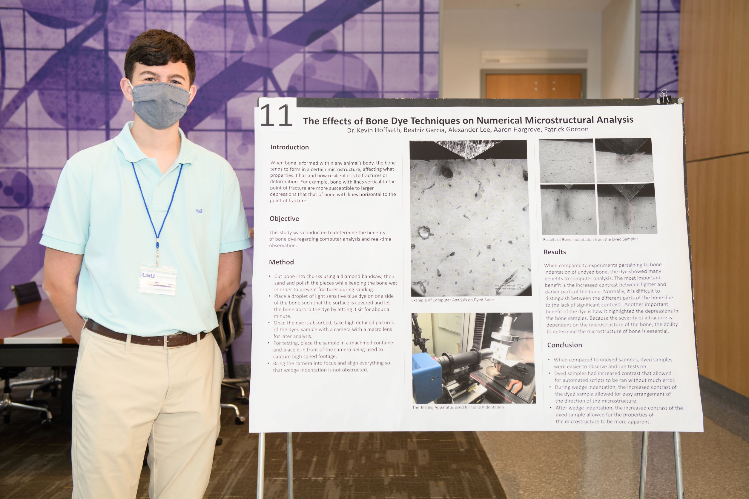 Student in blue shirt posing with poster presentation