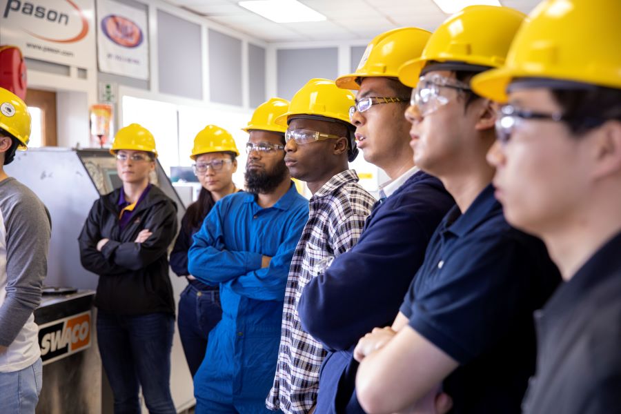 class of students with hard hats watch a demonstration