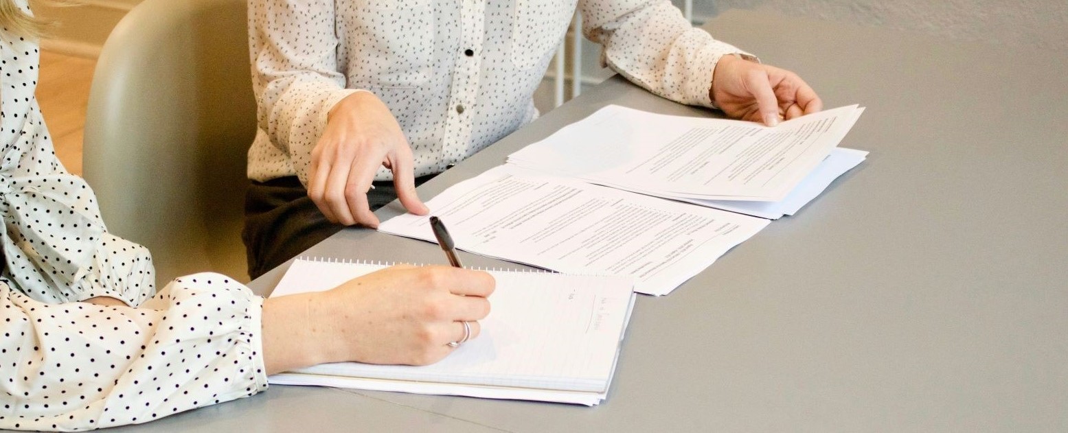 closeup of two people's hands as they leaf through paperwork