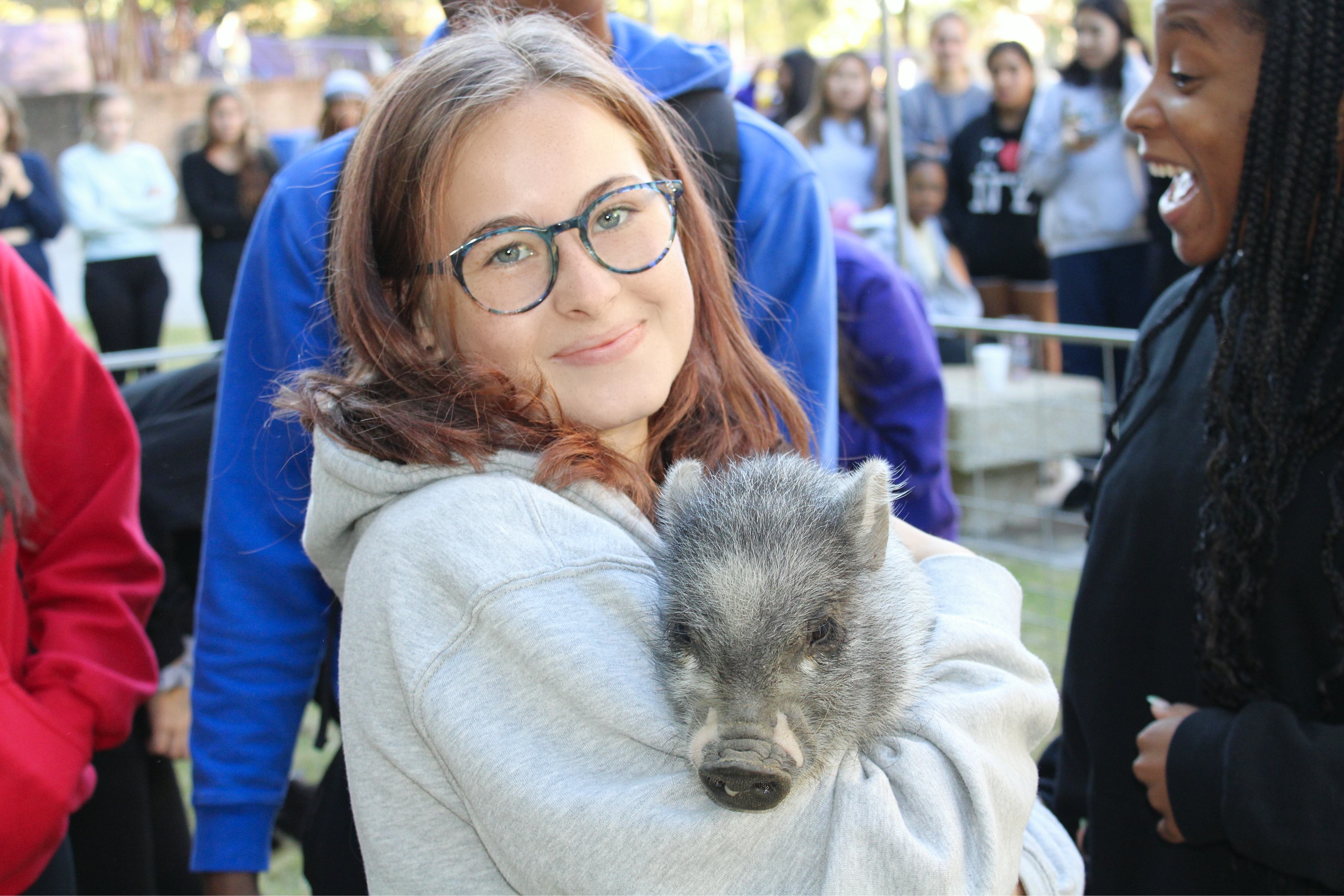 Student holding a pig at Cypress Hall event