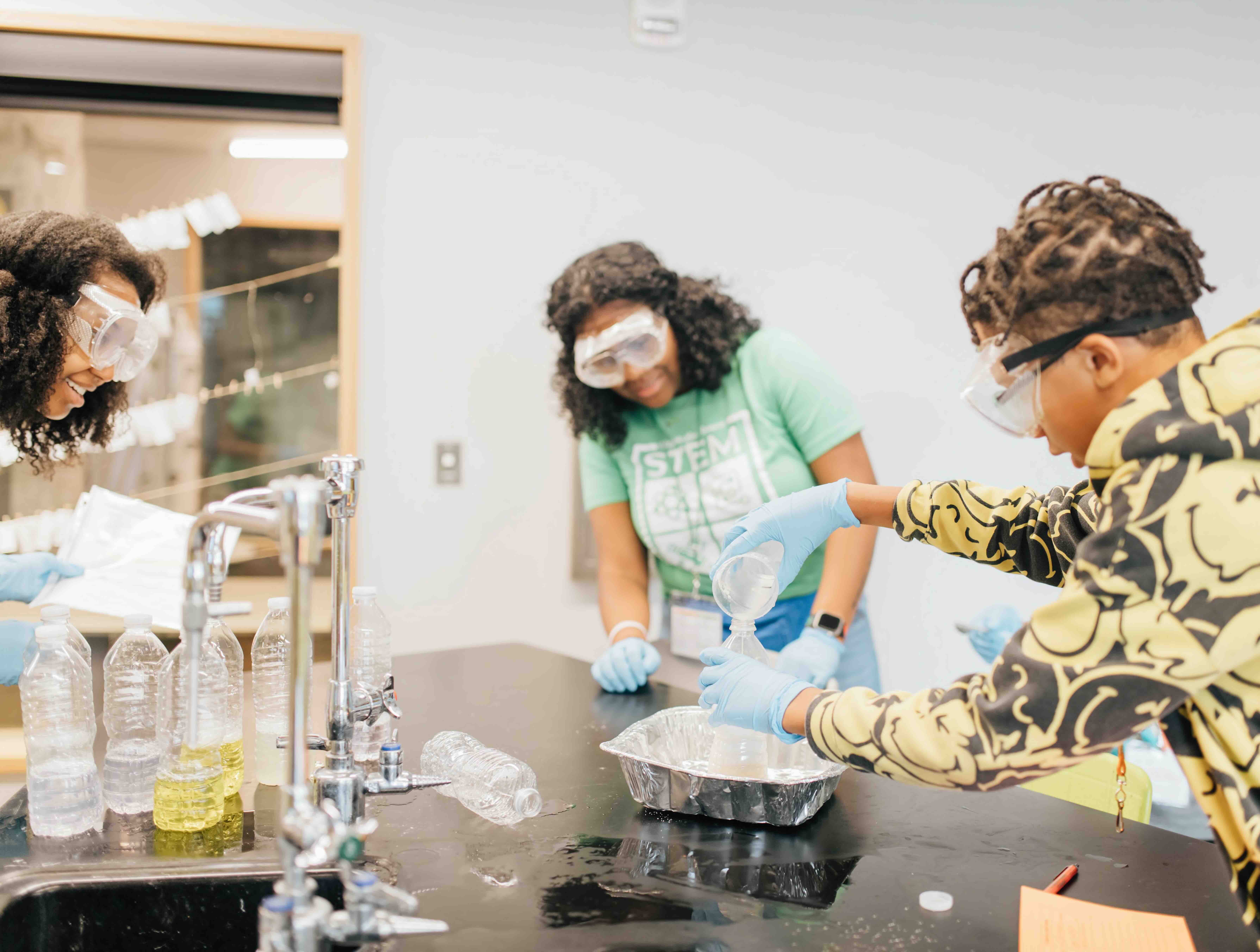 Tailenn demonstrating a science experiment to a group of engaged middle school students.