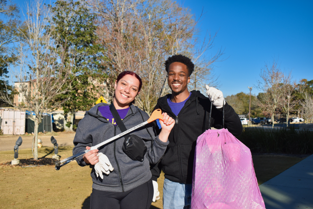 two students holding bags for clean up
