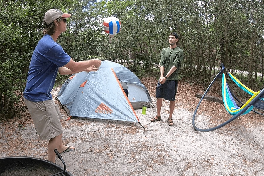 two students camping and playing volleyball